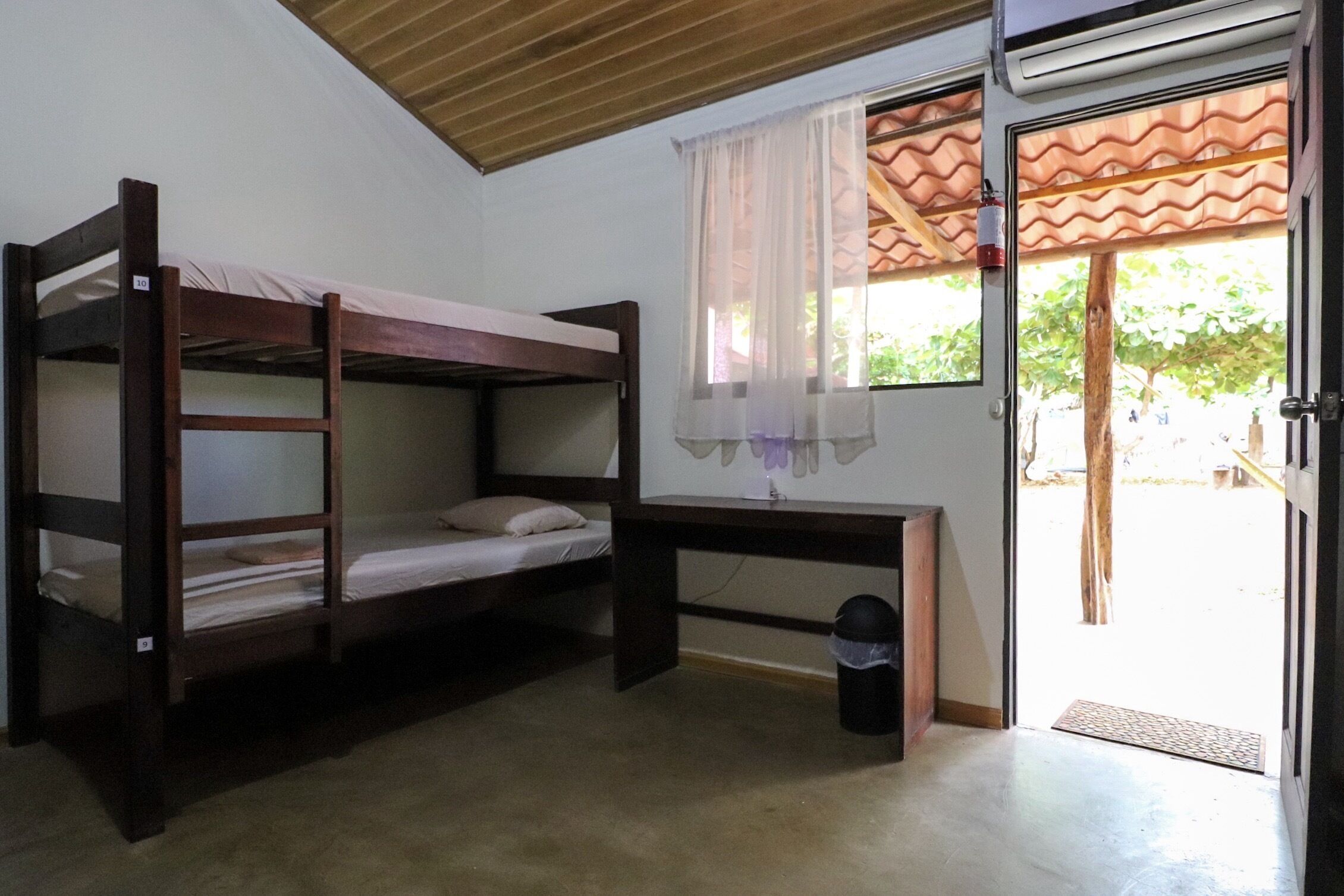 A bunk bed room with a desk and a window with curtains.