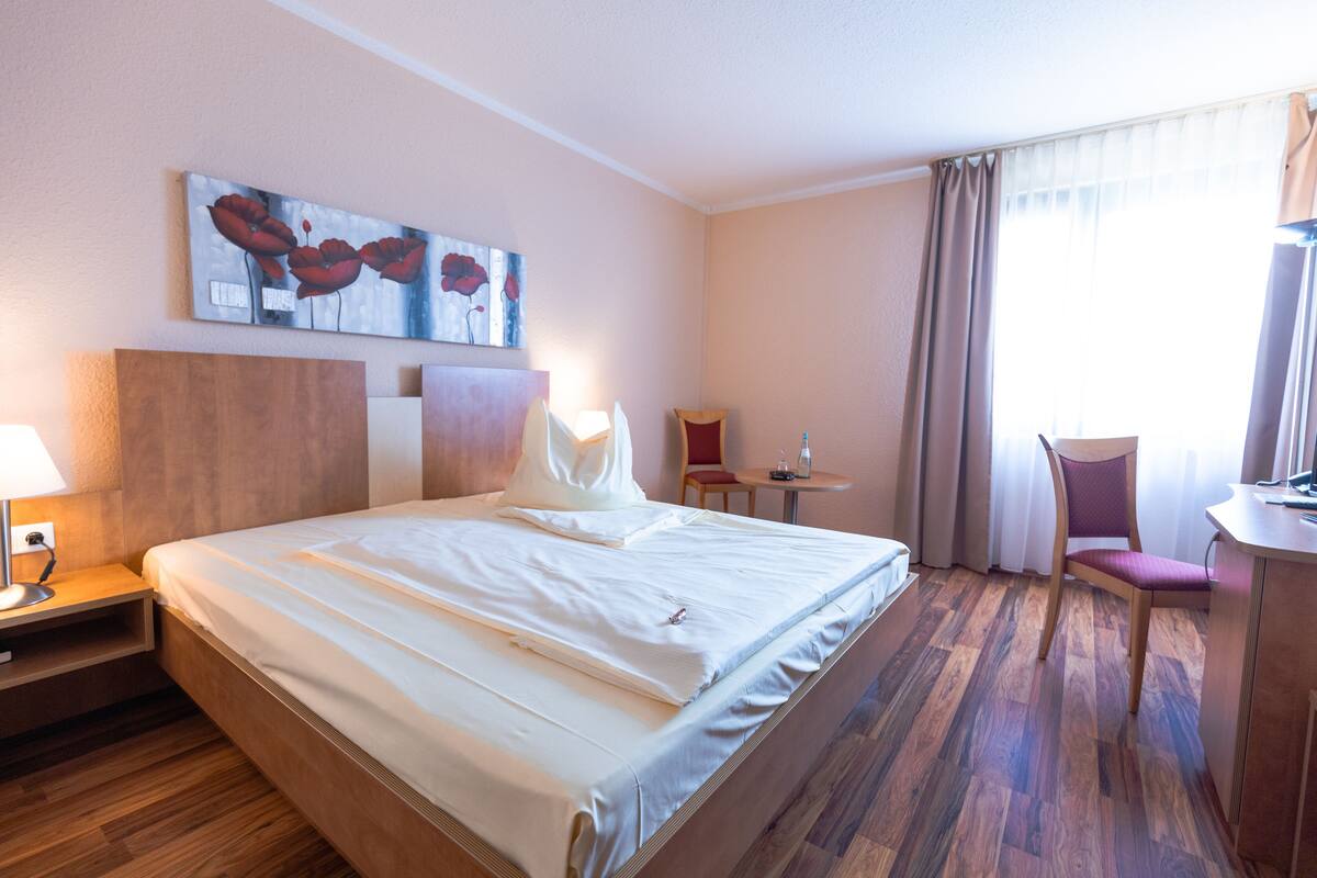 Ein Hotelzimmer mit einem großen Bett, einem Schreibtisch, einem Stuhl und einem Gemälde an der Wand.
