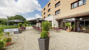Ein Hotelinnenhof mit Außenbestuhlung, Blumentöpfen und einem Schild mit der Aufschrift 'Mutter'.