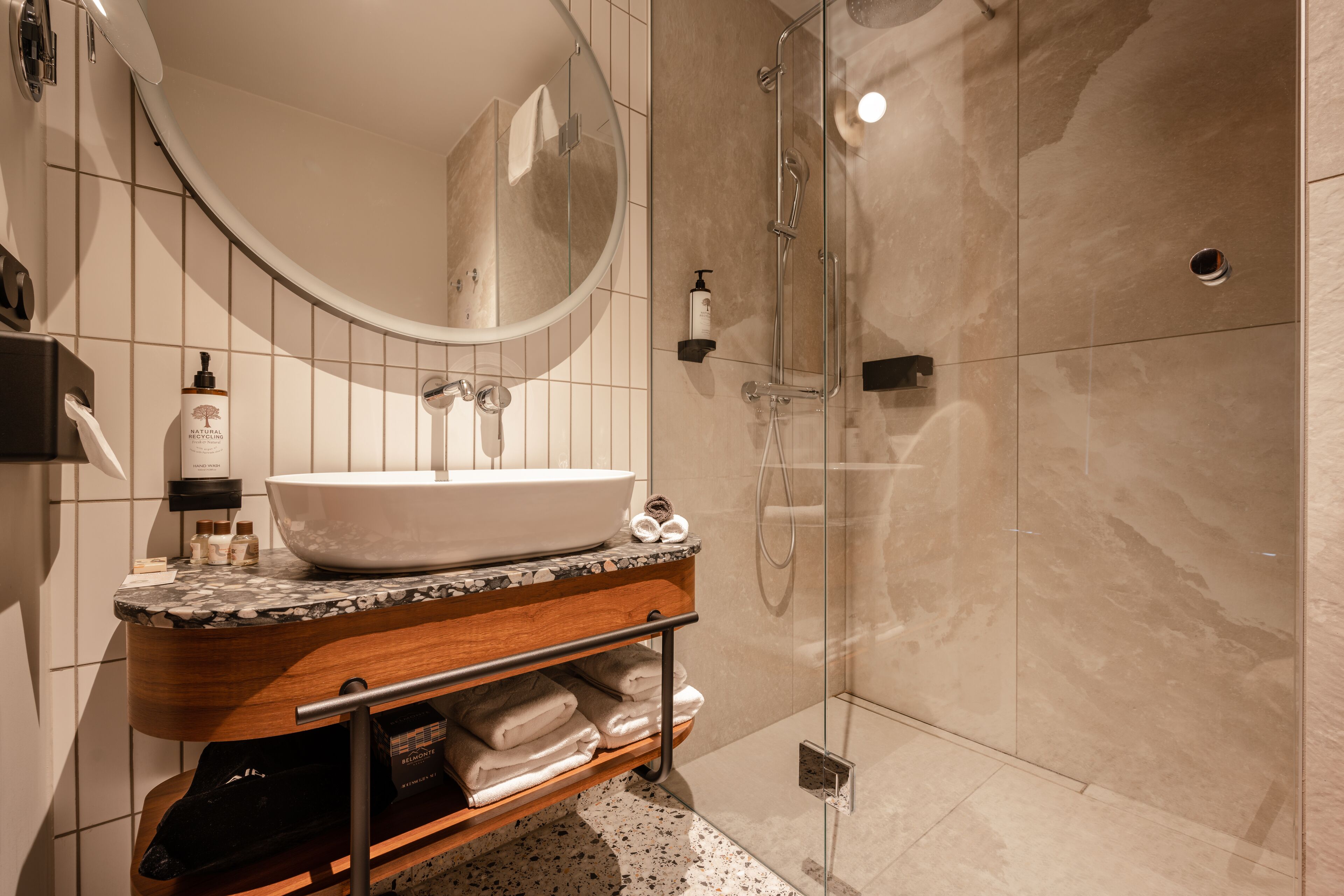 A modern bathroom with a large sink, mirror, and shower.