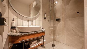 A modern bathroom with a large sink, mirror, and shower.