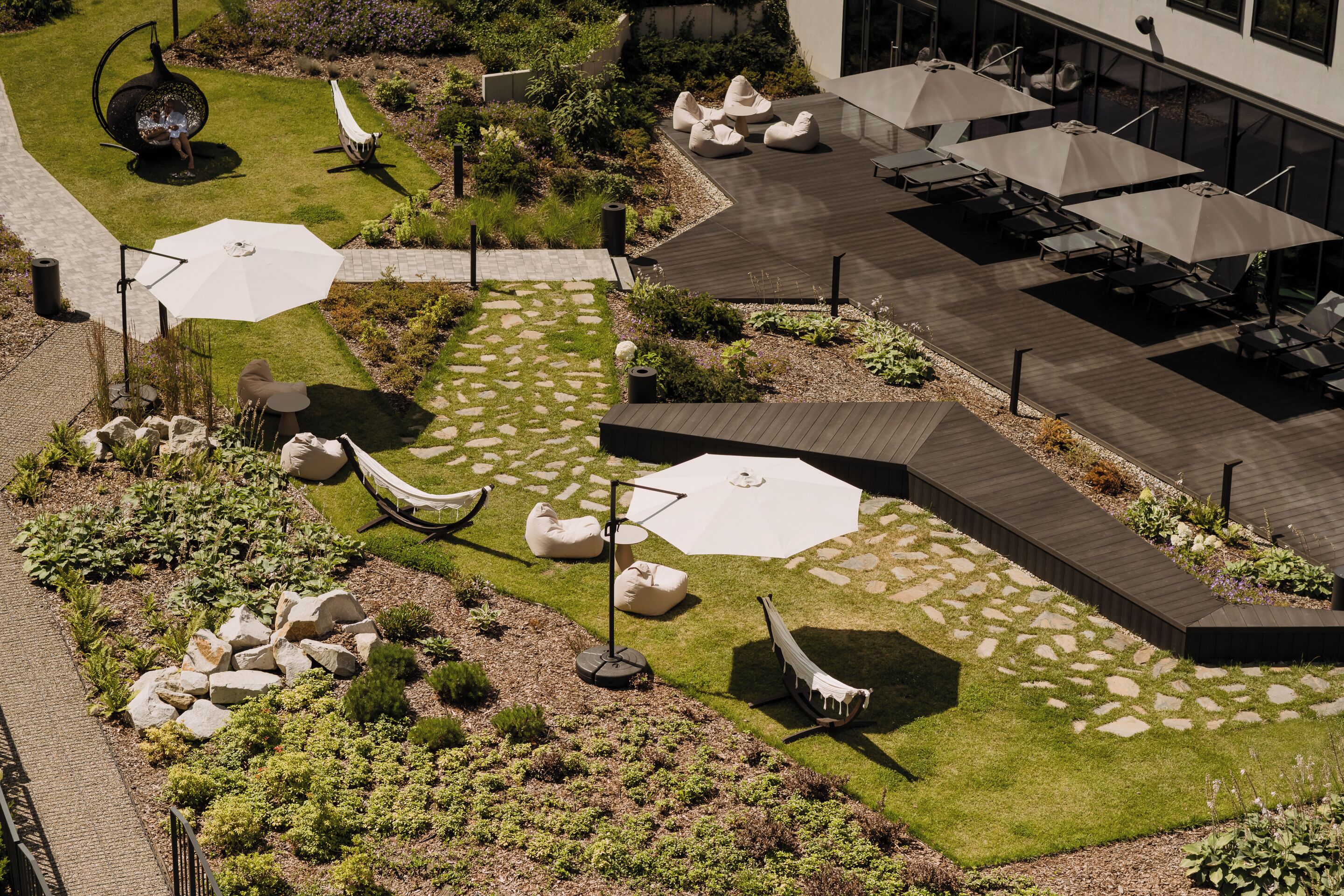 Un patio al aire libre con asientos, sombrillas y un jardín.