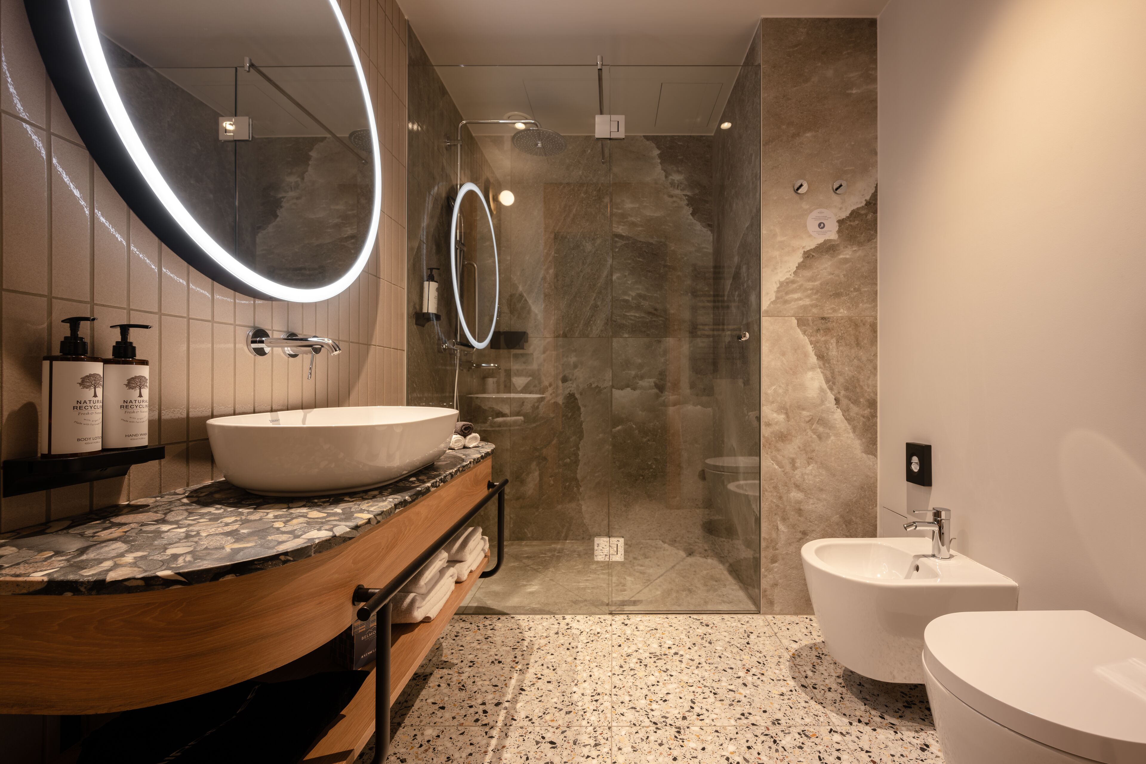 Une salle de bain moderne dotée d’un grand lavabo ovale, d’une baignoire sur pieds, d’une douche à parois de verre et d’un lavabo indépendant sur colonne.