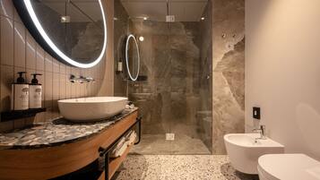 Une salle de bain moderne dotée d’un grand lavabo ovale, d’une baignoire sur pieds, d’une douche à parois de verre et d’un lavabo indépendant sur colonne.