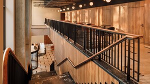 A modern staircase with a wooden finish and metal railings, leading to a seating area with tables and chairs. - BELMONTE Hotel Krynica-Zdrój (Krynica-Zdroj)