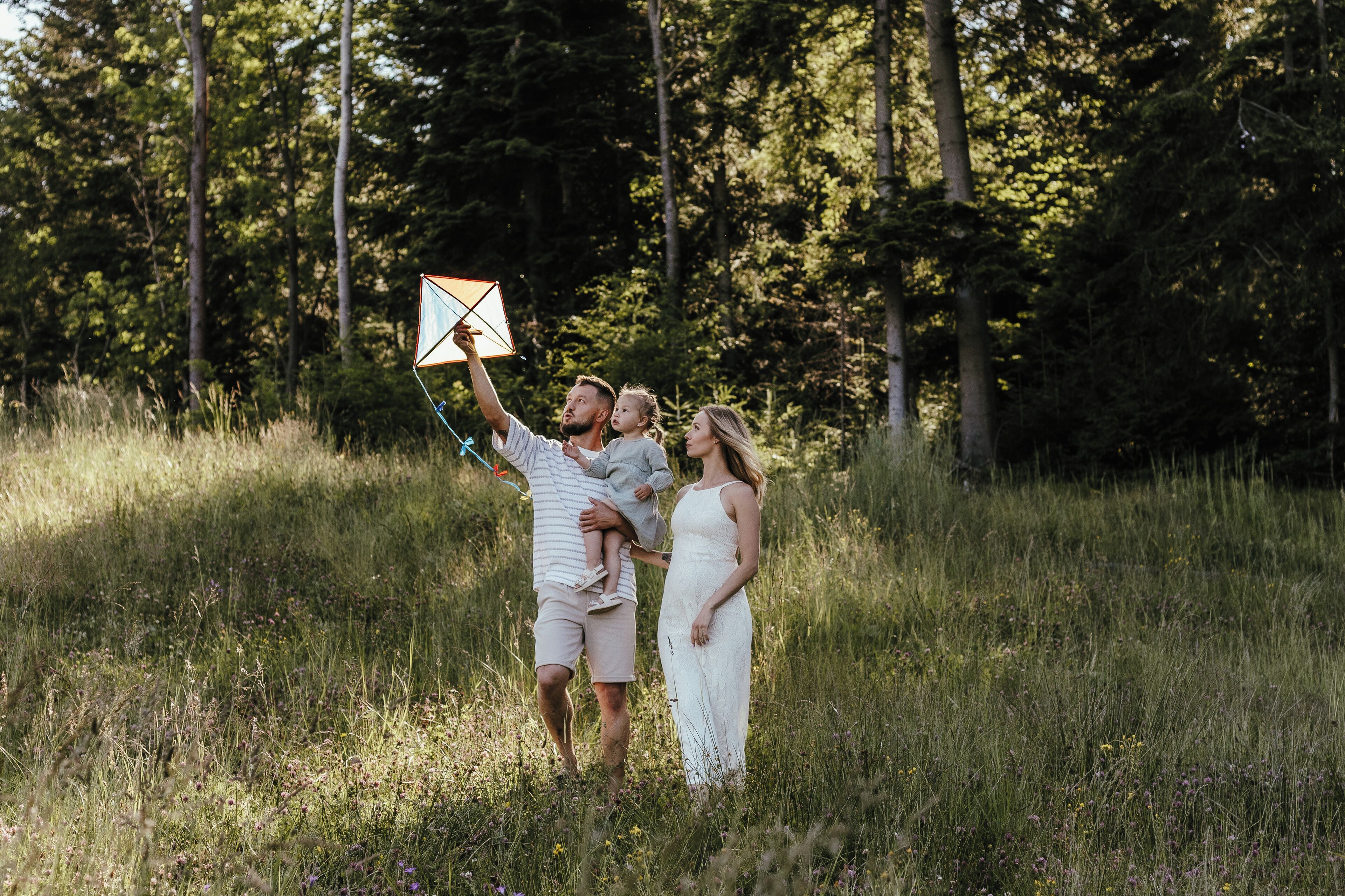 En familie i en græsmark med træer i baggrunden.