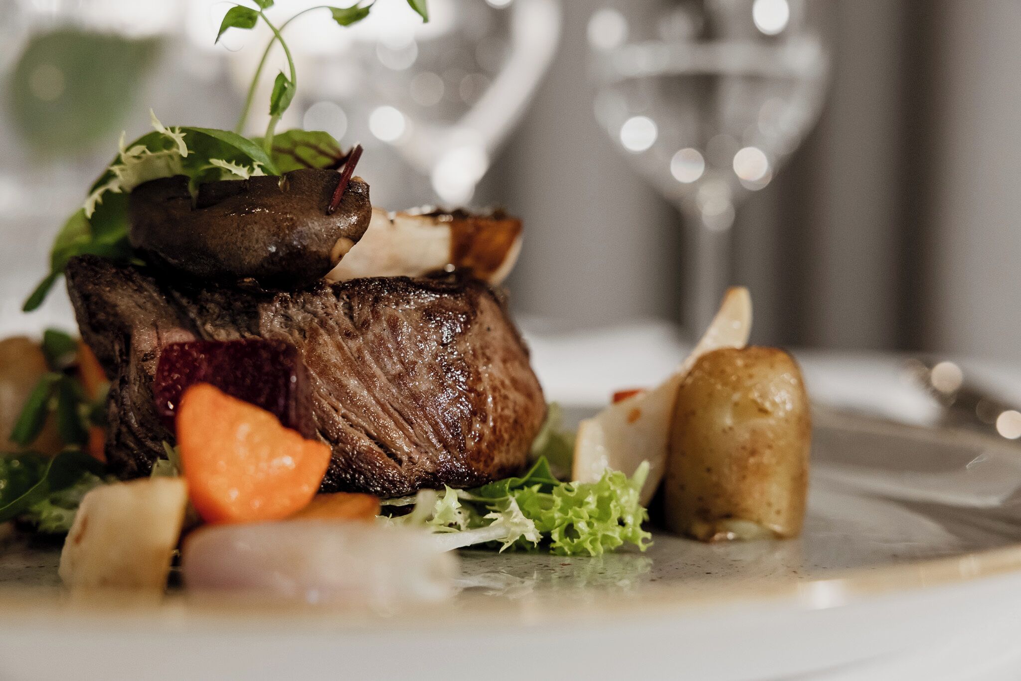 A steak with vegetables and a glass of wine on a plate.