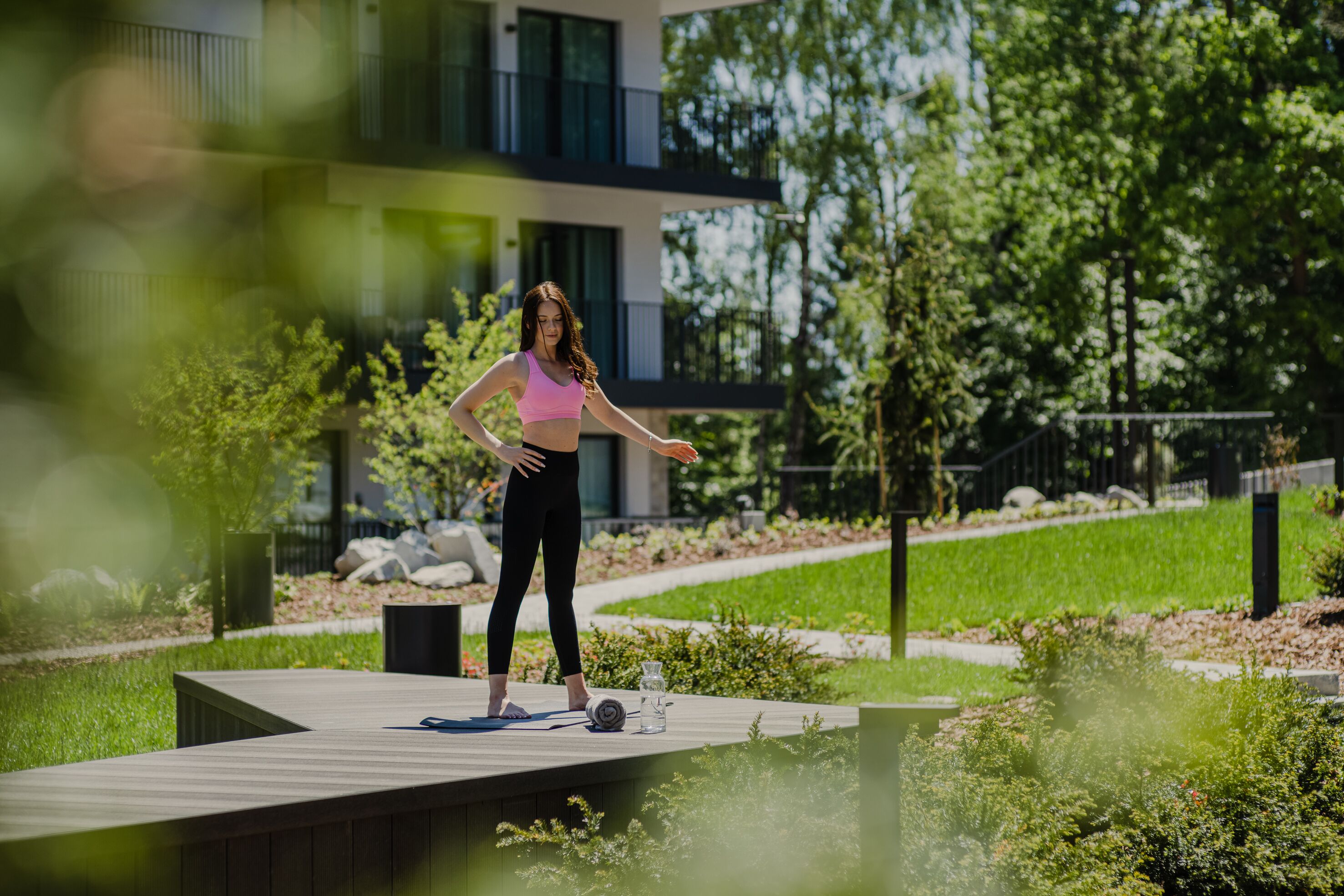 A person exercising on a wooden deck with a yoga mat and a water bottle.