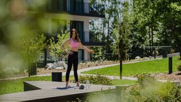 A person exercising on a wooden deck with a yoga mat and a water bottle.