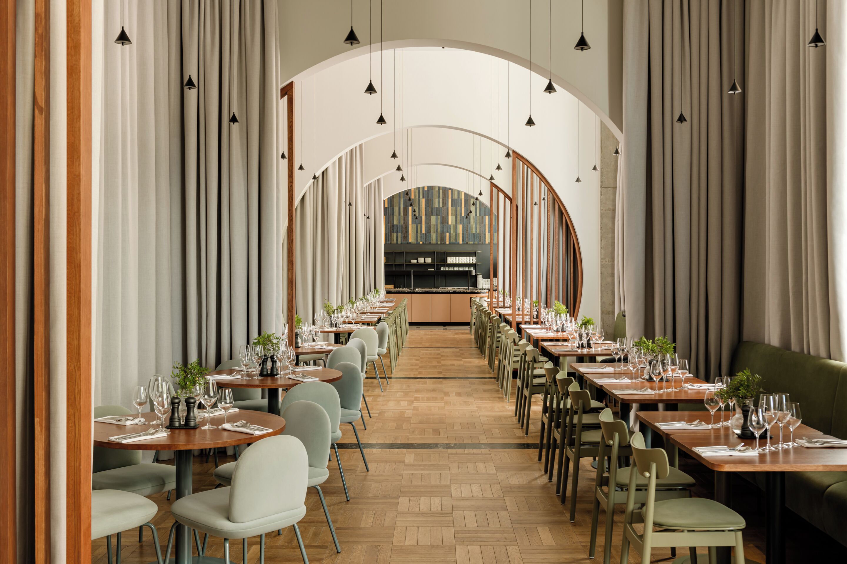 A restaurant with a long, open dining area, wooden tables, and chairs.