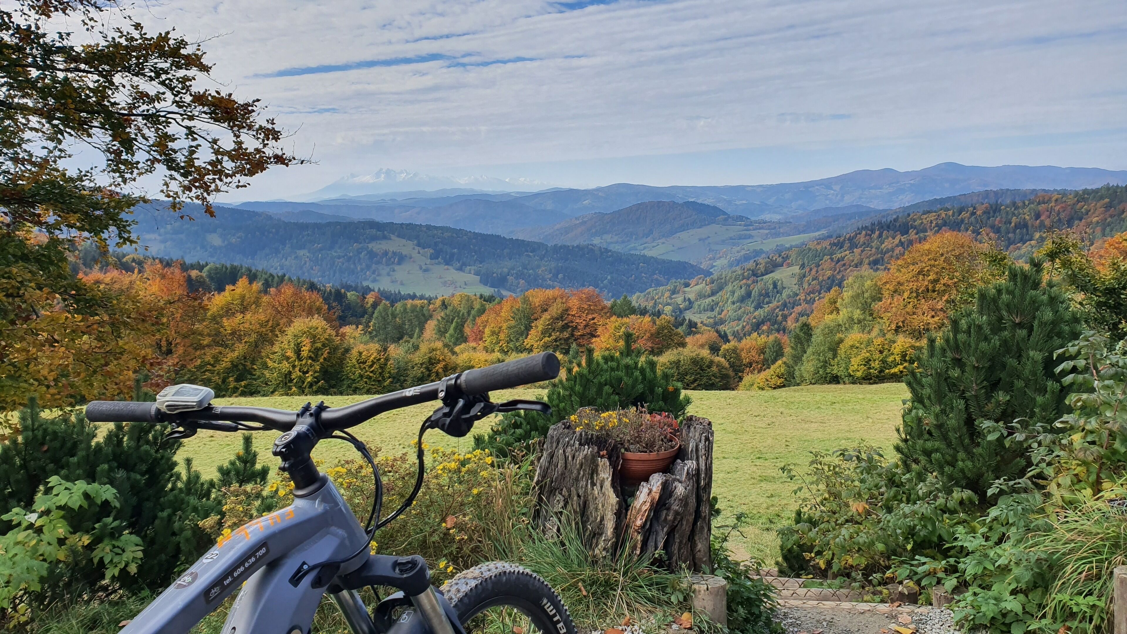 A mountain bike parked in a natural setting with a view of rolling hills and autumn foliage.
