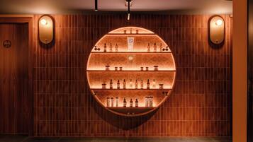 Un présentoir circulaire mural, composé de différentes bouteilles, probablement une sélection de boissons alcoolisées, dans une pièce aux murs lambrissés et dotée d’un éclairage encastré.