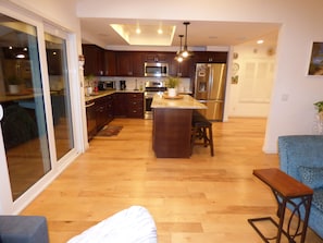 A modern kitchen with dark wooden cabinets, stainless steel appliances, and a central island. - Remodeled one story pool home, hiking trails, lake, beach & more.. (Agoura Hills)