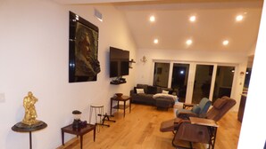 A living room with a sofa, armchairs, a coffee table, a TV, and a statue. - Remodeled one story pool home, hiking trails, lake, beach & more.. (Agoura Hills)