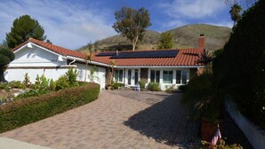 A house with a red-tiled roof, a paved driveway, and a garden with an American flag. - Remodeled one story pool home, hiking trails, lake, beach & more.. (Agoura Hills)