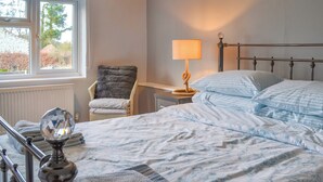 A bedroom with a bed, a chair, a lamp, and a window. - 3 bedroom accommodation in North Walsham (North Walsham)
