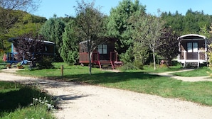 A campground with several cabins, a dirt path, and surrounding greenery.