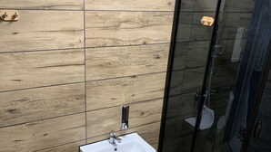 A modern bathroom with a wooden floor, a white sink, and a glass shower enclosure. - charming Cataleya hostel in a quiet and beautiful neighborhood (Lublin)
