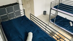 A dormitory room with bunk beds, a desk with a chair, a television mounted on the wall, and a door. - charming Cataleya hostel in a quiet and beautiful neighborhood (Lublin)
