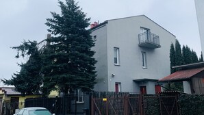 A modern building with a balcony, a large evergreen tree, and a gated entrance. - charming Cataleya hostel in a quiet and beautiful neighborhood (Lublin)