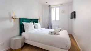 A hotel room with a bed, bedside tables, a TV, and a window with curtains. - Appartement8P/Full Equipped/Bonnenouvelle/Bourse (Paris)