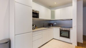 A modern kitchen with white cabinetry, a microwave, a sink, and an oven. - Appartement8P/Full Equipped/Bonnenouvelle/Bourse (Paris)