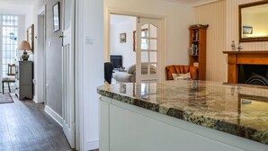 A kitchen with a granite countertop, a fireplace, and a dining area with a chair and table. - 3 bedroom accommodation in Keswick (Keswick)