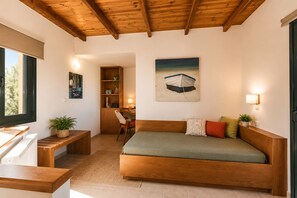 Een gezellige kamer met een houten plafond, een bed met kussens, een bureau met stoel, een boekenkast en een schilderij van een boot.