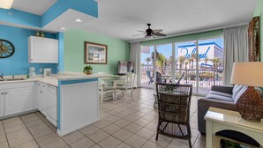 Una cocina moderna con armarios blancos, una zona de comedor con sillas blancas y vistas a un edificio con la palabra 'Island' escrita.