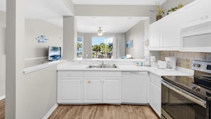 A modern kitchen with white cabinetry, a built-in oven, and a large island with a sink.