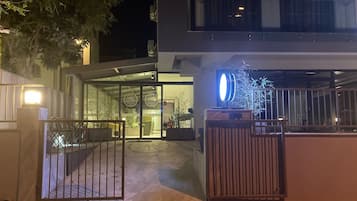 Un bâtiment moderne doté d’une entrée en verre, d’une grille métallique et d’un intérieur bien éclairé.