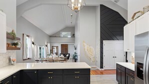 Una cocina moderna con armarios oscuros, una isla grande y un diseño de techo original.