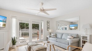 A spacious living room with a light grey sofa, a white coffee table, and a ceiling fan. - Miramar Beach Condo: Pool, Hot Tub, Beach (Miramar Beach)