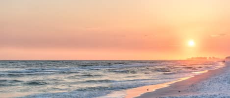 Una playa con olas y un atardecer.