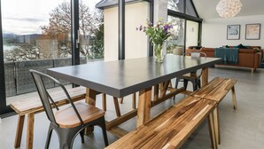 A modern dining area with a large table, wooden benches, and pendant lighting. - Kessock (Windermere)