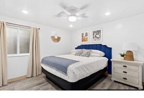 A bedroom with a bed, bedside table, and ceiling fan.