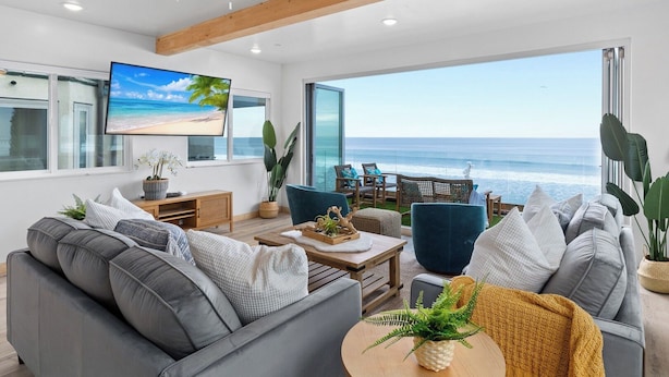 A modern living room with a large TV, comfortable seating, and a view of the ocean. - Prime Waterfront Retreat P807-2 (Oceanside)