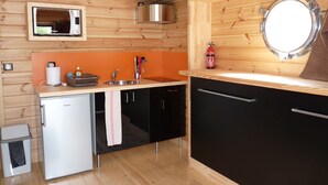A compact kitchen with a microwave, sink, and a small refrigerator. - Toue cabanée (Chamberet)