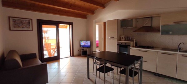A compact living space with a dining area, kitchenette, and a television.