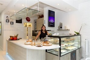 Un café moderno con una vitrina de vidrio llena de pasteles y un mostrador con diversas opciones de comida.