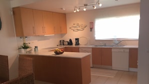 Una cocina moderna con armarios de madera, una isla central, un fregadero y un lavavajillas.