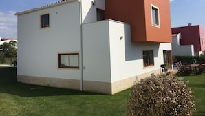 Una casa moderna de dos pisos con techo plano, paredes exteriores blancas y una pared de acento roja.