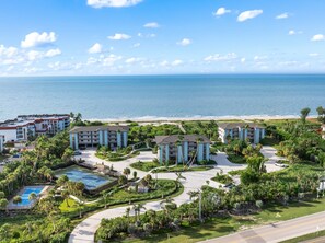 A resort with multiple buildings, a swimming pool, and a beach view.