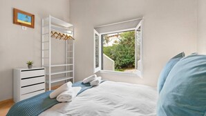 Une chambre avec un lit, une fenêtre, une armoire et une petite plante.