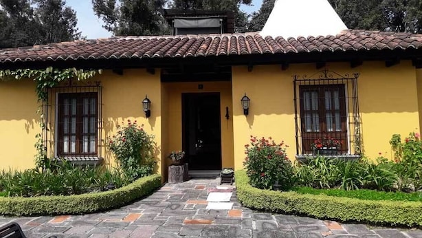 A yellow building with a tiled roof, a white dome, and a stone pathway leading to the entrance. - Casa Antigua (Antigua Guatemala)