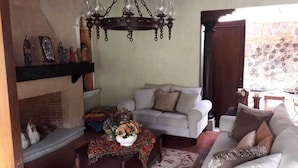 A cozy living room with a fireplace, a sofa set, a coffee table, and a chandelier. - Casa Antigua (Antigua Guatemala)