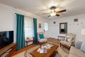 Relax in this inviting living room with a large flat-screen TV, comfortable sofa, and matching armchair.