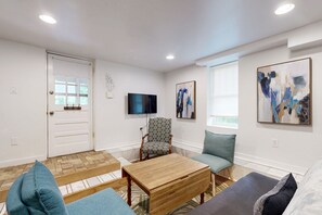 Relax in this stylish living space, featuring a comfortable sofa, a flat-screen TV, and abstract artwork on the walls.