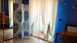 Quarto com parede azul, mesa de madeira, cadeira e cama com cabeceira estampada.