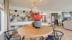 A modern dining area with a round wooden table, black chairs, and a central vase with red flowers. - Best Luxury Riverfront Home w/ Private Pool & Dock (Bullhead City)
